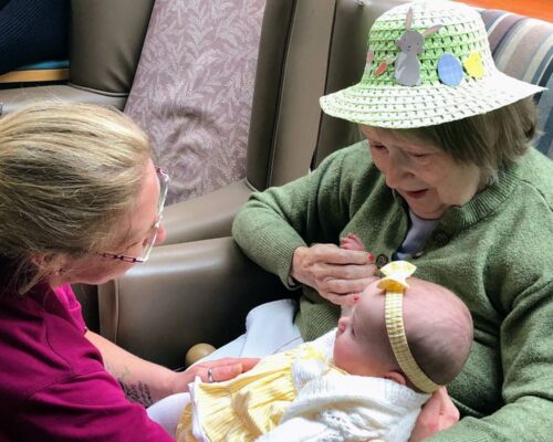 Resident holds baby at 'Mother and baby' visit from Interglow