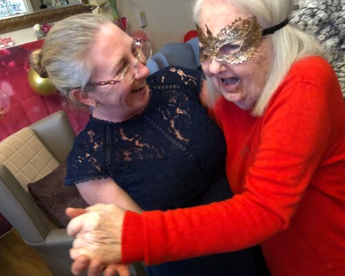 Two women hugging at the Valentine's Masked Ball
