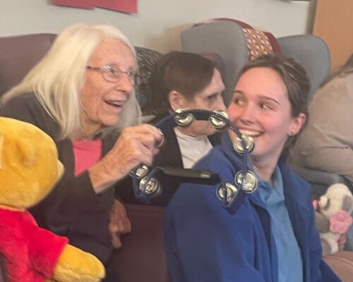 Resident shakes tambourine at Baby Glow event