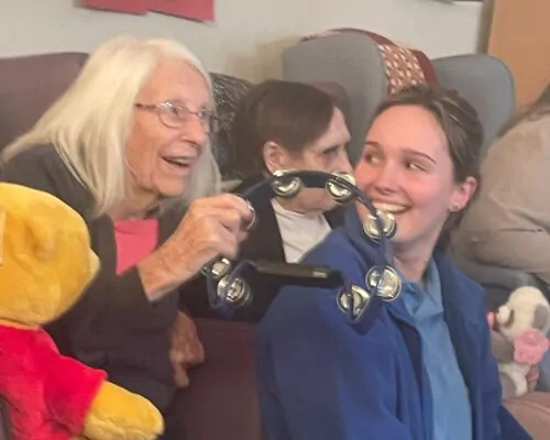 Resident shakes tambourine at Baby Glow event